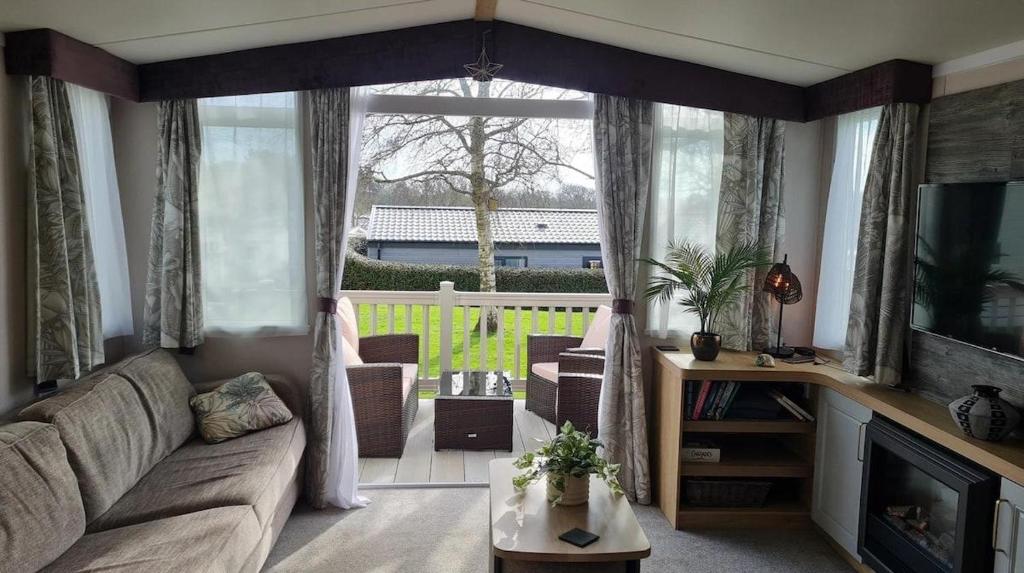 a living room with a couch and a large window at STYLISH MODERN CONTEMPORARY PET FREE HOLIDAY HOME ON AWARD WINNING SHOREFIELD COUNTRY PARK Edge New Forest ENTERTAINMENT AND LEISURE PASSES INCLUDED in Milford on Sea