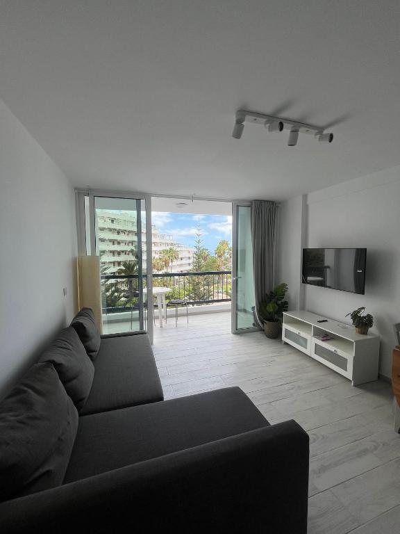 Una sala de estar con un sofá negro y un televisor. en ¡Tal y como Hawaii!, en Playa Fañabe