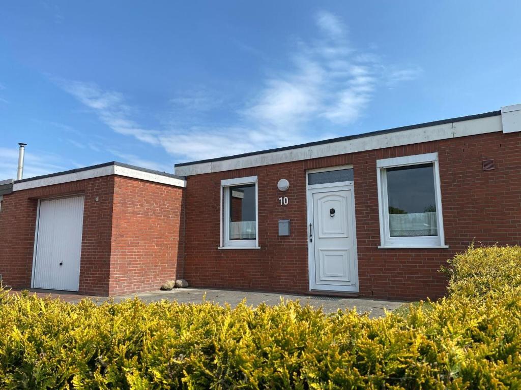 a brick building with a white door and windows at Bungalow in Dornumersiel in Dornumersiel