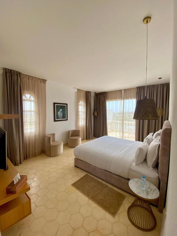 a large bedroom with a large white bed and windows at Villa La Falaise in Oualidia