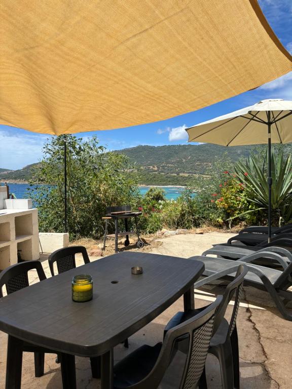 a wooden table with chairs and an umbrella at Apparemment bord de mer 2 à 5 personnes in Sagone