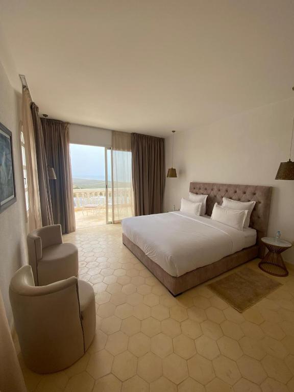 a bedroom with a bed and a chair and a window at Villa La Falaise in Oualidia