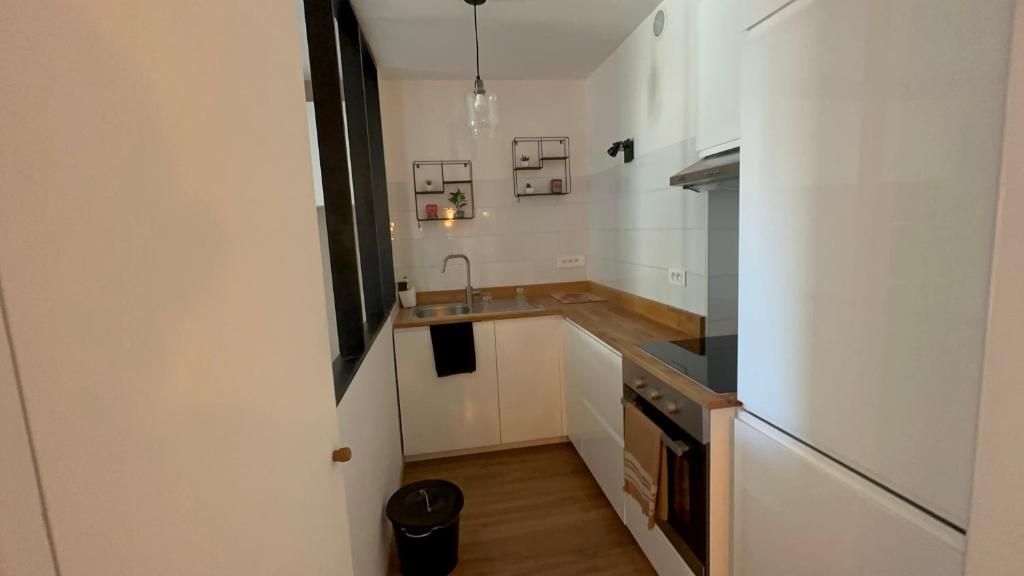 une petite cuisine avec des armoires blanches et un évier dans l'établissement Appartement Marseille 5ème avec terrasse, à Marseille
