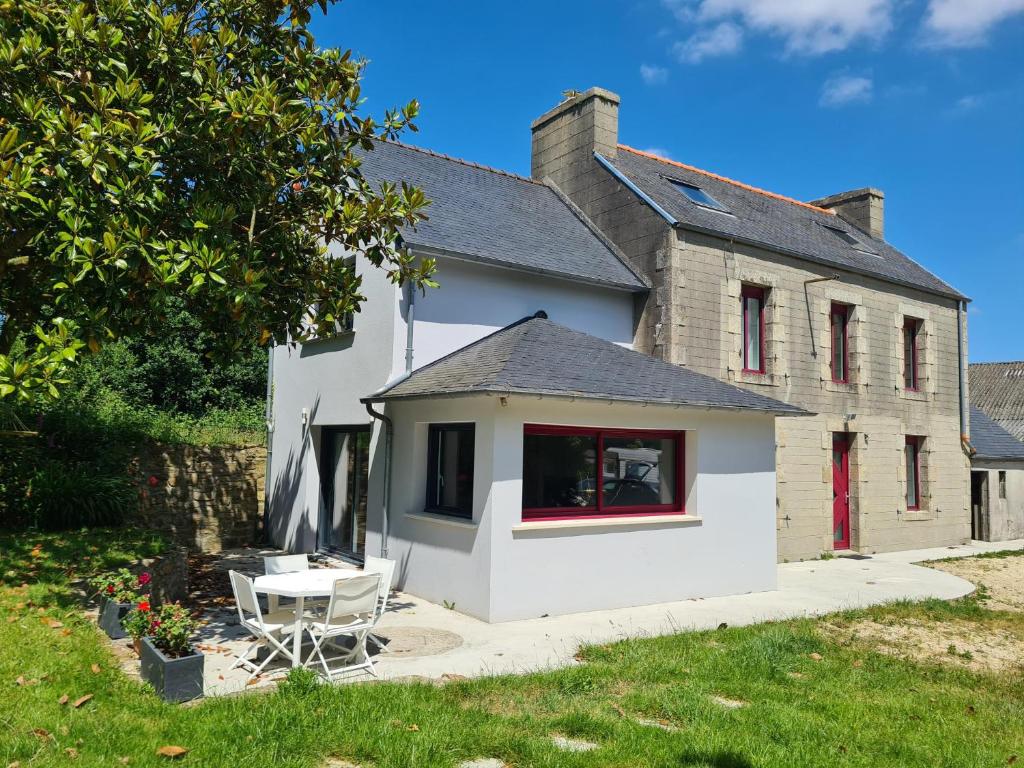 une maison blanche avec une table et une chaise dans l'établissement Grande maison champêtre à 2 min de la voie express, à Landivisiau