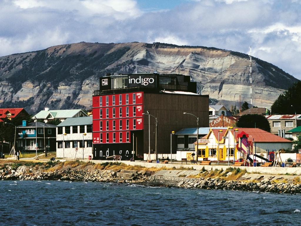 a red building with a sign on it next to the water at NOI Indigo Patagonia in Puerto Natales