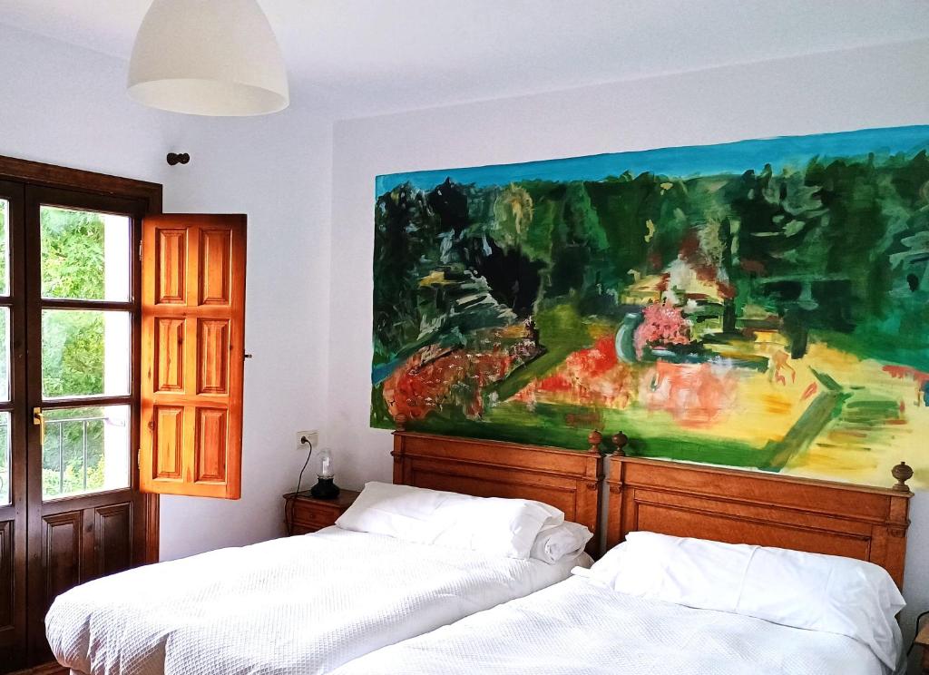 a bedroom with two beds and a painting on the wall at Hotel rural El Jardin del Conde in Puerto de Béjar