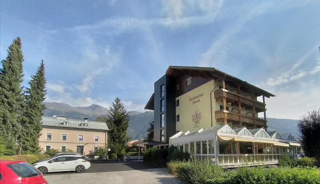 a building with a car parked in a parking lot at Dolomitenhotel Lienz in Lienz