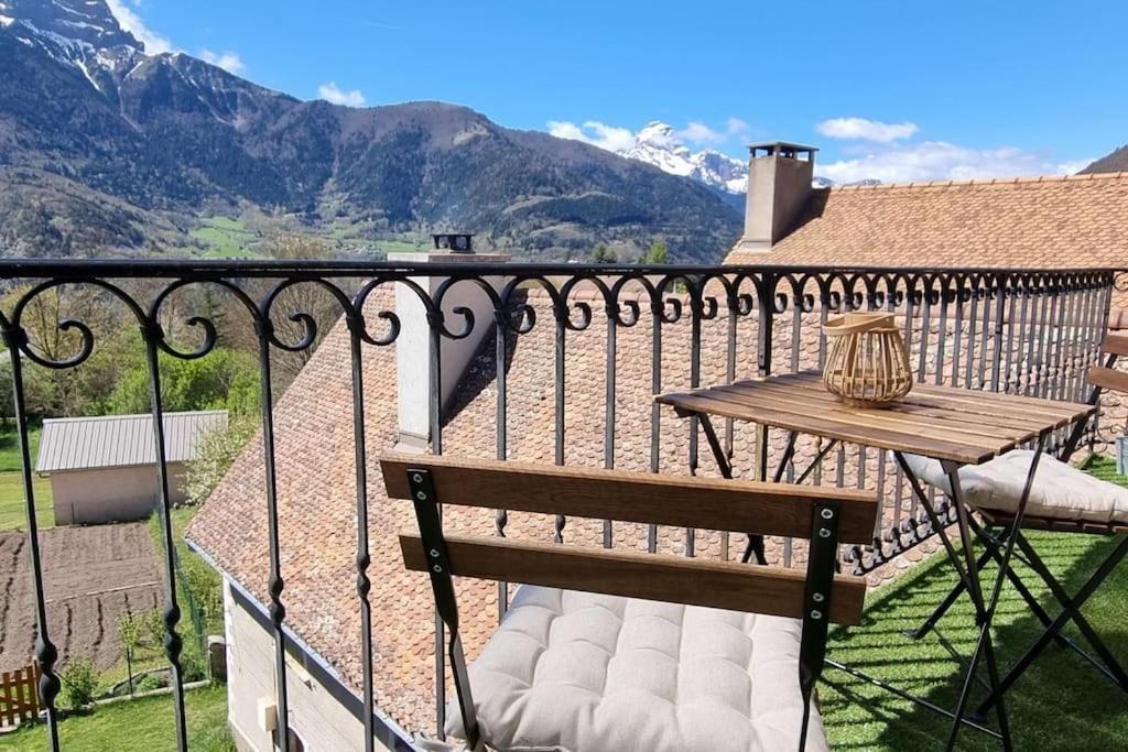 una panca di legno seduta su un balcone con tavolo di Le Cocon Asprion a Aspres-lès-Corps