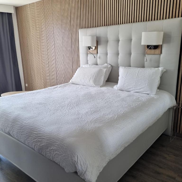 - un grand lit blanc avec deux oreillers et deux lampes dans l'établissement Studio Naturiste Adam Résidence Le Jardin D'Eden, au Cap d'Agde