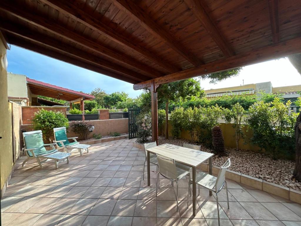 a patio with chairs and a table and a wooden pergola at Villetta climatizzata con giardino e al mare in Torre dell'Orso