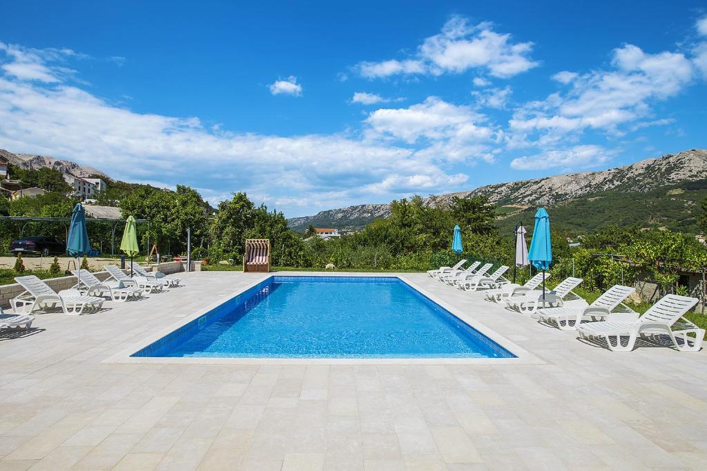 a swimming pool with lounge chairs and umbrellas at Apartments Juranić in Baška