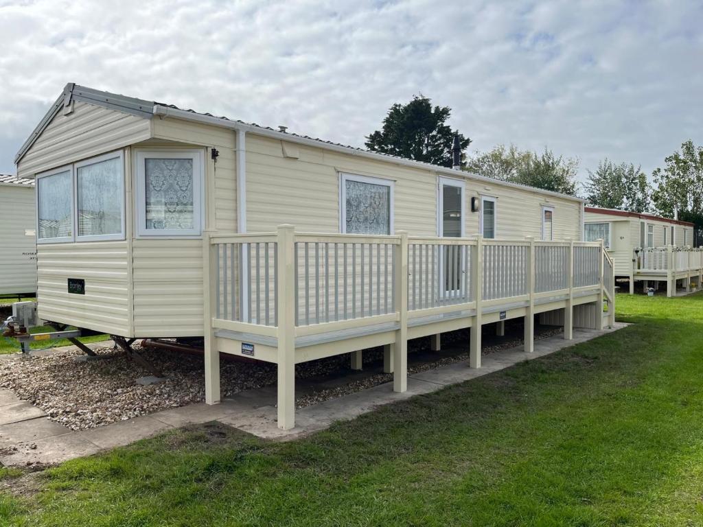 a large white mobile home with a wooden porch at Goodwin's static caravan in Mablethorpe