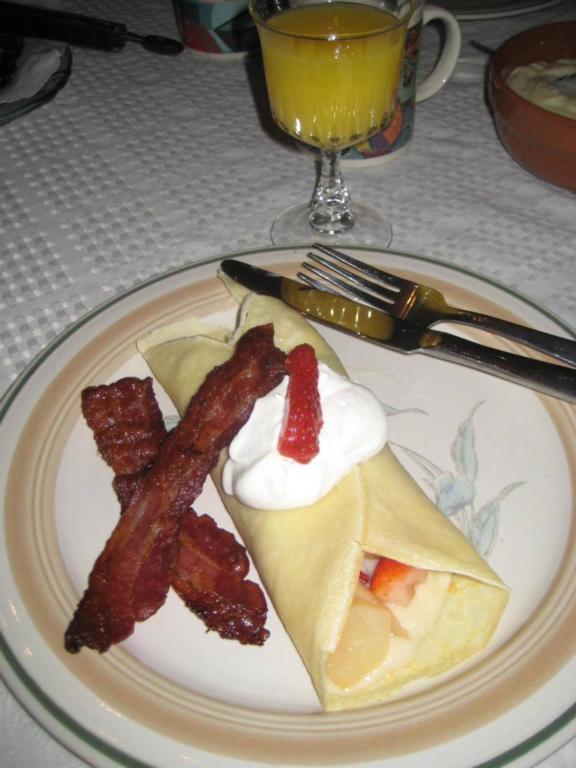a plate of food with bacon and eggs and a drink at Phoenix House B&B in Stettler