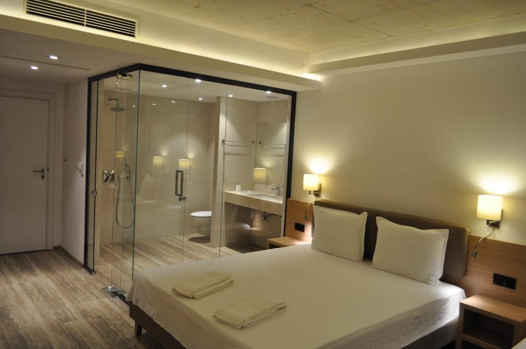 Schlafzimmer mit einem Bett und einer Glasdusche in der Unterkunft Hotel Tyulenovo in Tyulenovo