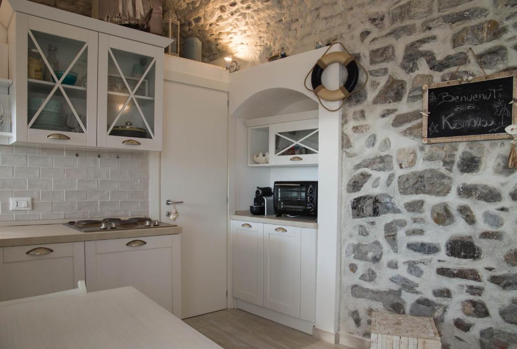 cocina con armarios blancos y pared de piedra en KAMBUSA LOFT - Mono fronte mare, en Santo Stefano al Mare