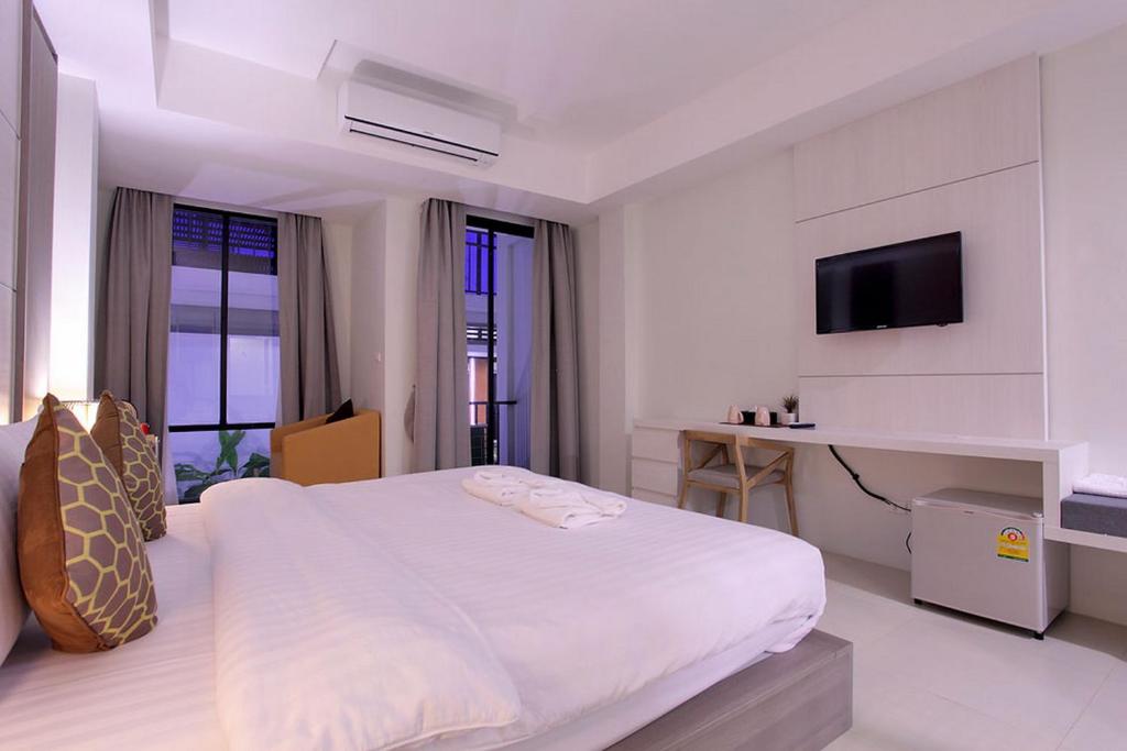 a white bedroom with a large bed and a tv at Win D Hotel in Nakhon Ratchasima