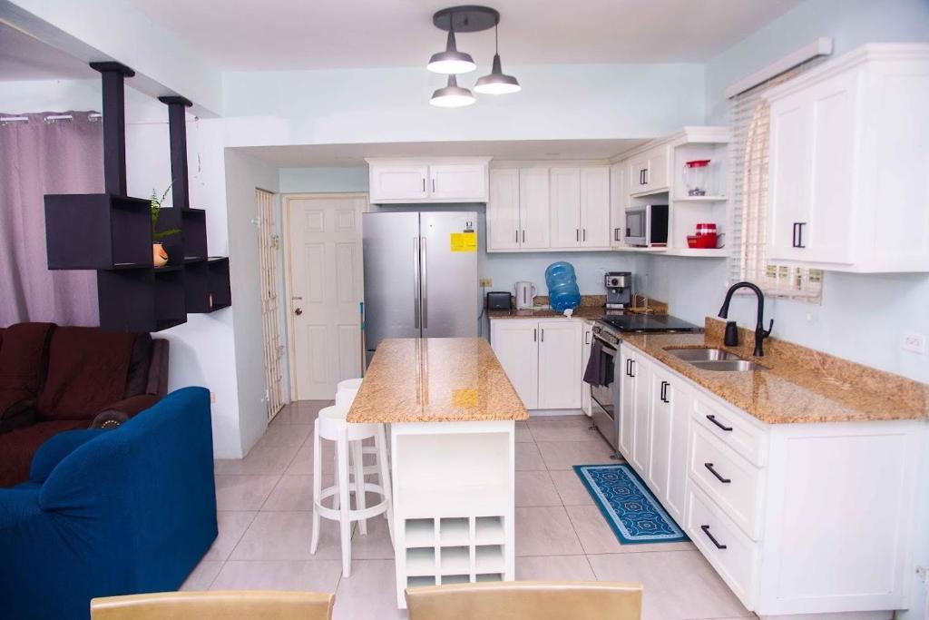 a kitchen with white cabinets and a blue couch at Tranquil Oasis in Mona in Kingston