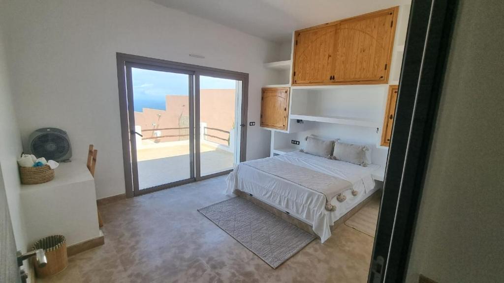 a bedroom with a bed and a door to a balcony at Villa avec piscine Asilah, terrain de foot privative in Asilah