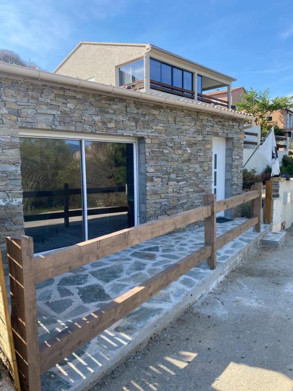une maison en pierre avec une clôture en bois dans l'établissement Villa, à Piedigriggio
