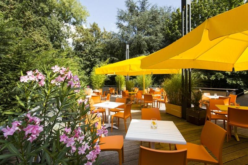 a restaurant with tables and chairs and yellow umbrellas at Jugendherberge City-Hostel Köln-Riehl in Cologne