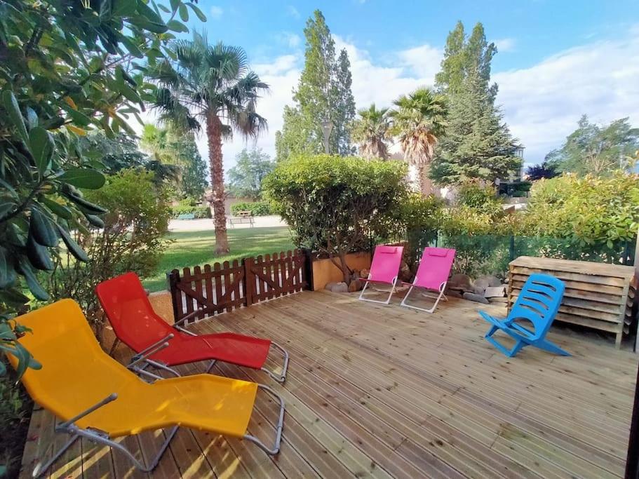 4 chaises colorées assises sur une terrasse en bois dans l'établissement Superbe T2 atypique climatisé rdc à 2mn de la Plage, à Saint-Cyprien