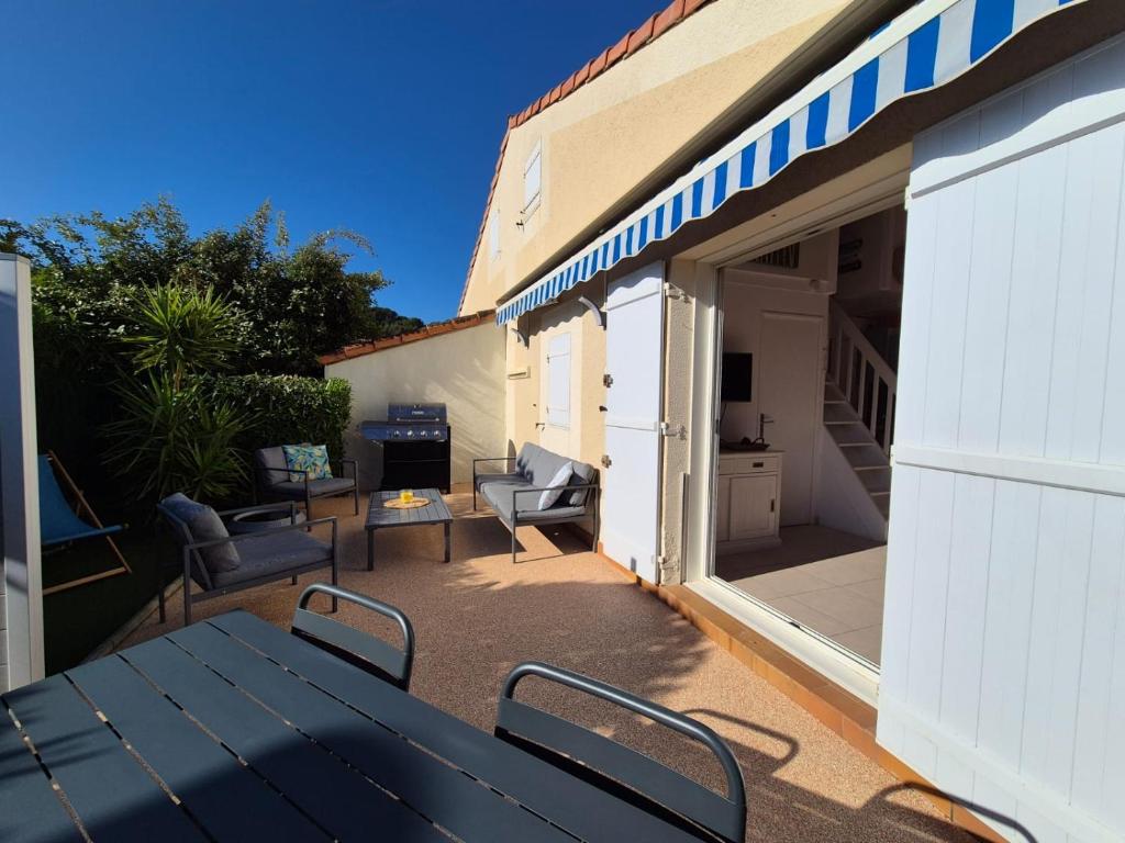 un patio con mesa negra y sillas y un edificio en Lou Mas Azur, en Le Lavandou