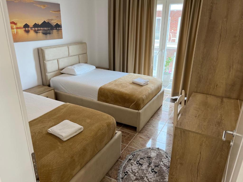 Cette chambre comprend 2 lits et une fenêtre. dans l'établissement Fishta apartments Q5 34, à Velipojë
