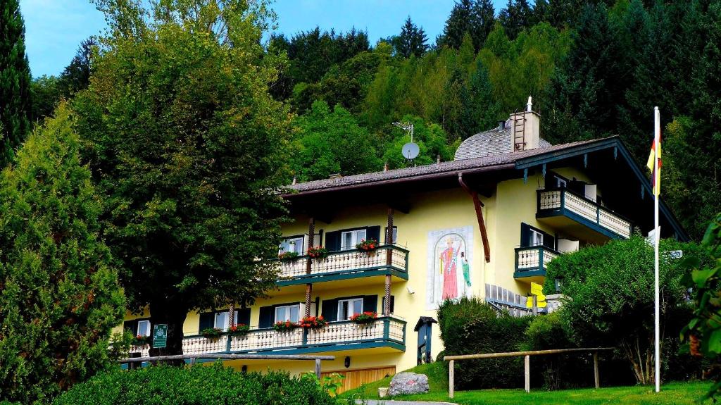 un grande edificio giallo con balconi e alberi di Berghaus - Der Westerhof Hotel a Tegernsee