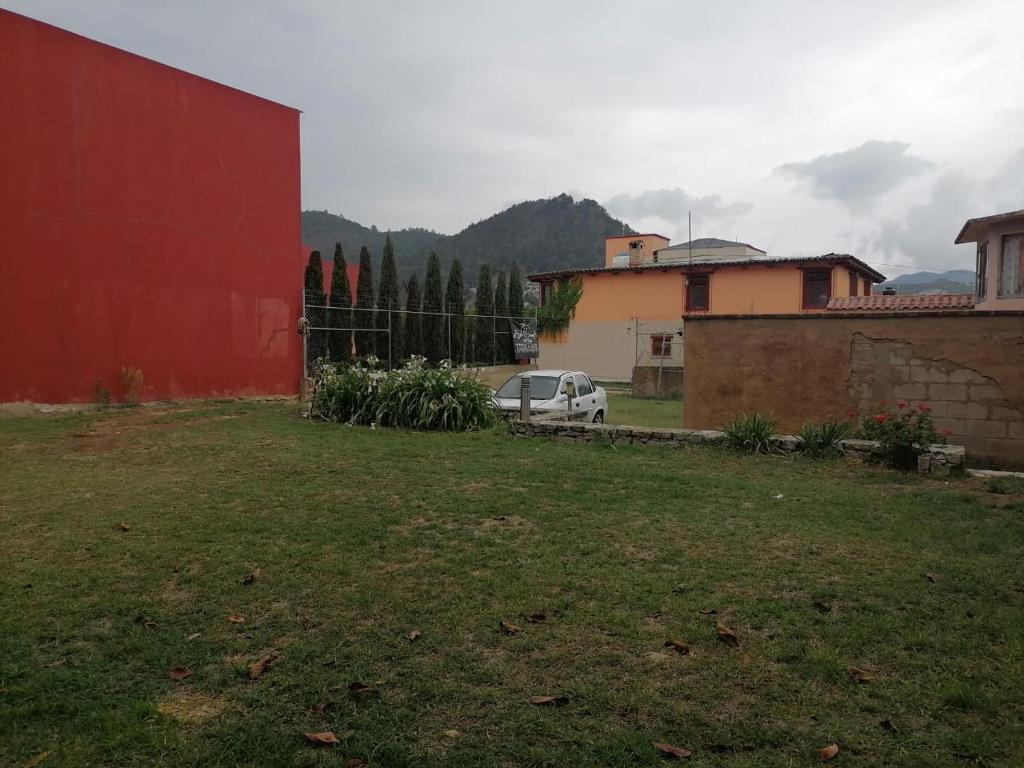 un'auto parcheggiata in un cortile accanto a un edificio rosso di Hotel Tierra Maya a San Cristóbal de Las Casas