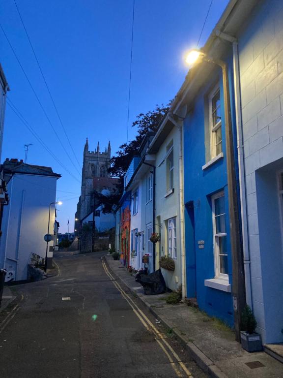 eine leere Straße mit blauen Häusern und einer Kirche in der Unterkunft "FISHERMAN'S" Seconds from the Harbour & town centre with unlimited free parking nearby in Brixham