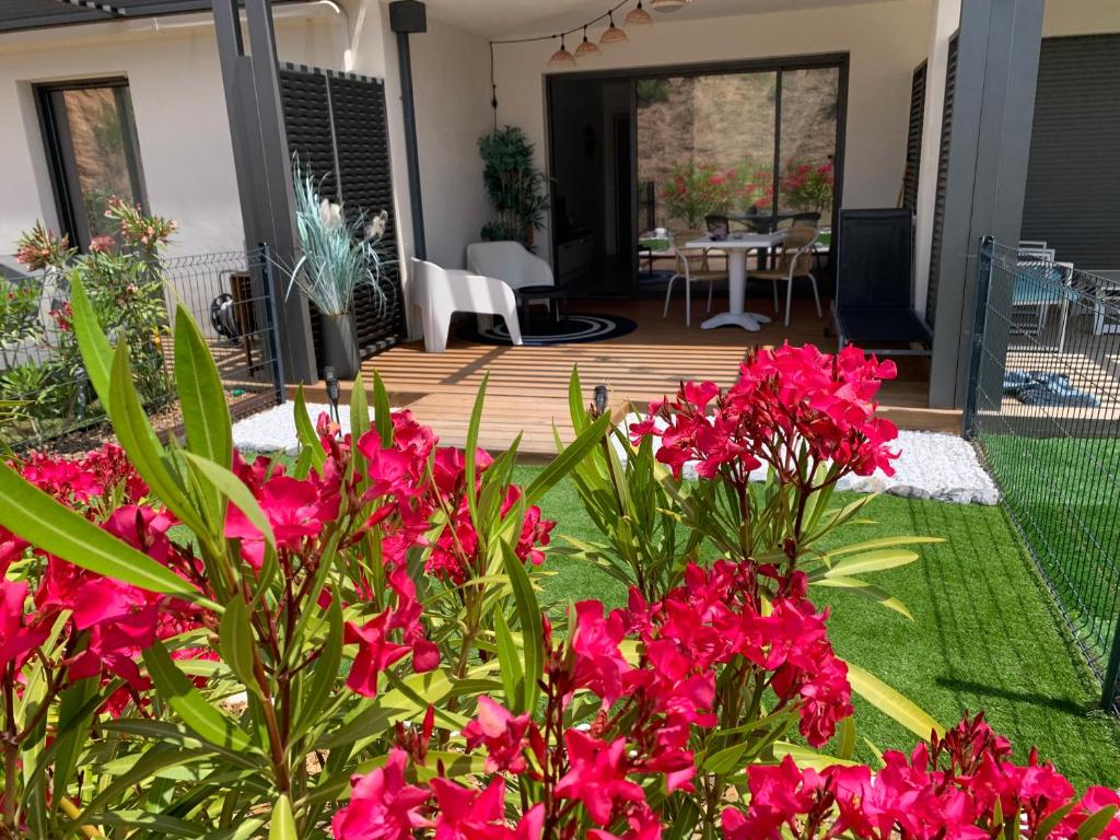 une terrasse avec des fleurs roses dans la cour dans l'établissement Stella mare à porticcio, à Porticcio