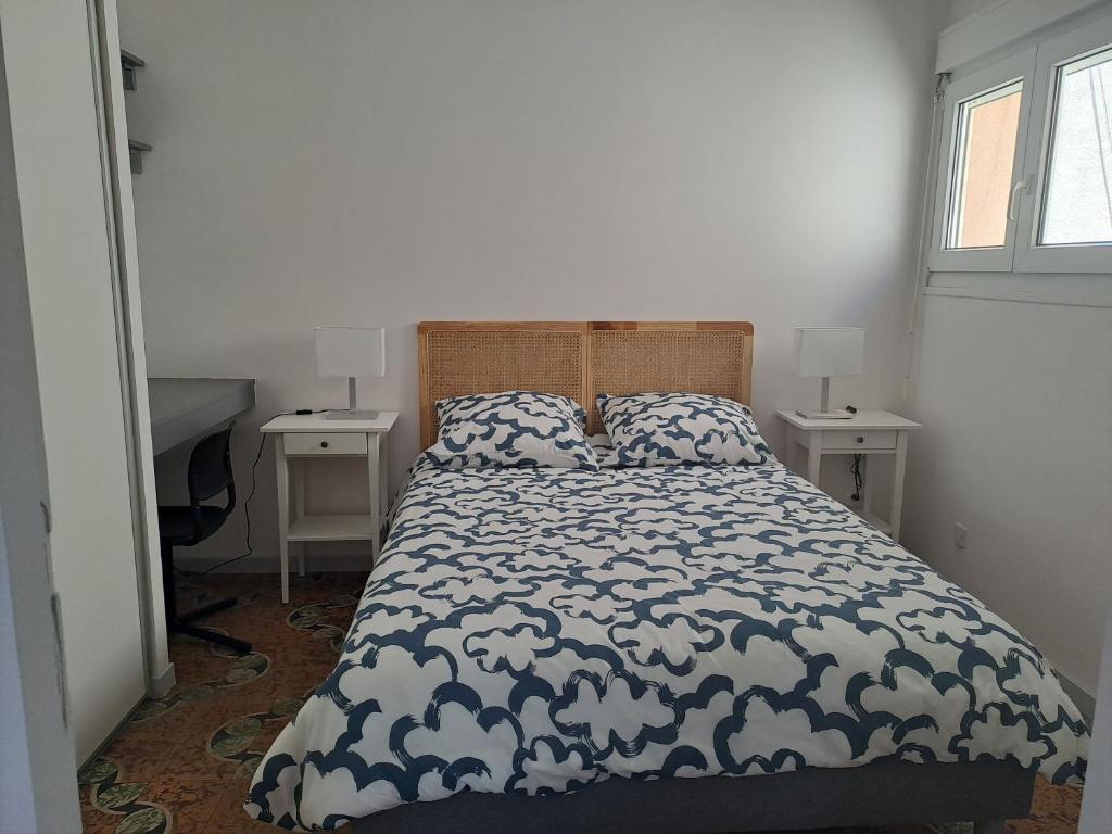 une chambre avec un lit avec une couette bleue et blanche dans l'établissement L'Oustal de Provence, à Sète