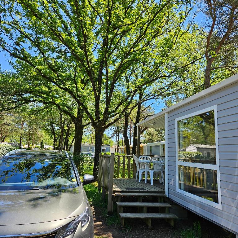 une voiture garée devant une maison avec terrasse couverte dans l'établissement MH-MAUFAY -- Mobil-Home -- Puy du Fou - 30 min, à La Boissière-de-Montaigu