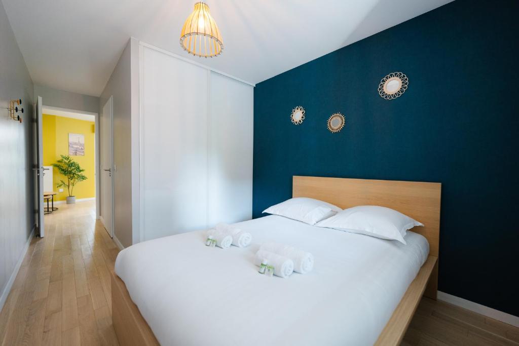 - une chambre avec un grand lit blanc et un mur bleu dans l'établissement Confort Absolu à Paris ,superbe appartement rénové 7 Chambres avec salles de Bain privatives, à Paris
