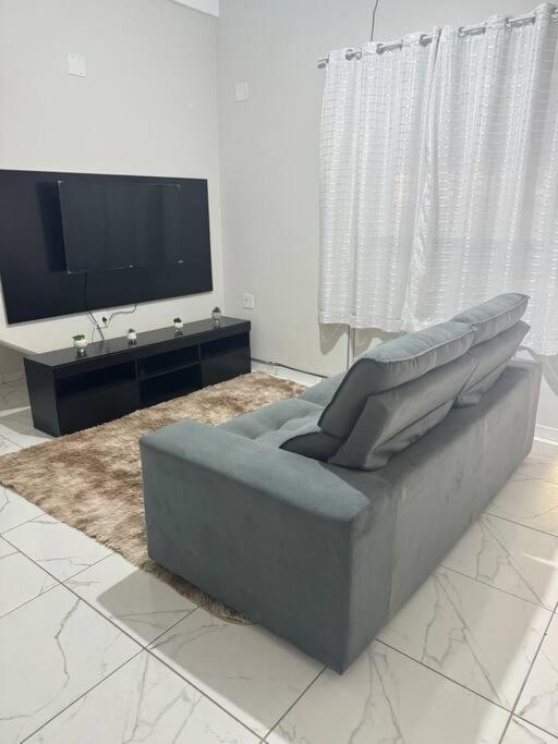 ein Wohnzimmer mit Sofa und Flachbildfernseher in der Unterkunft Casa Aconchego 6min basílica in Aparecida