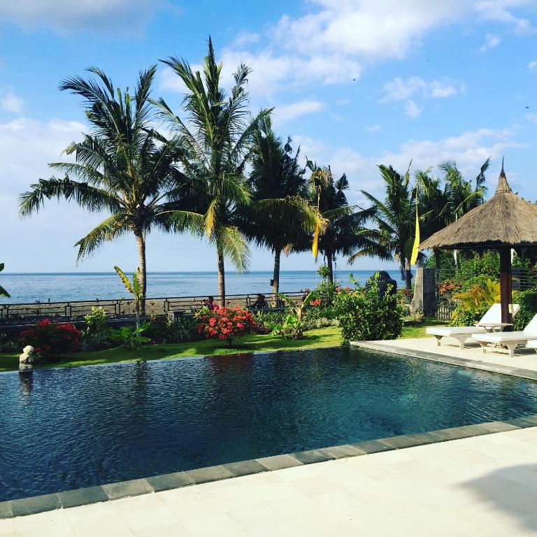a swimming pool with the ocean in the background at Villa Danison in Umeanyar