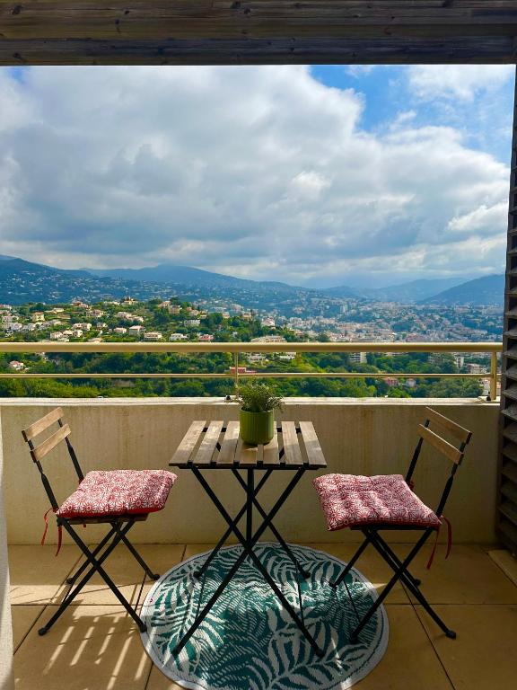 une table et deux chaises sur un balcon avec vue dans l'établissement Cosy studio avec parking et vue féerique, à Nice