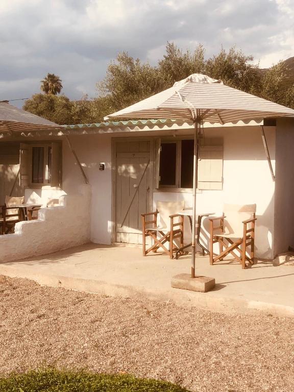 a white house with a table and an umbrella at Barreira Beachfront Rooms 7 in Kalamata