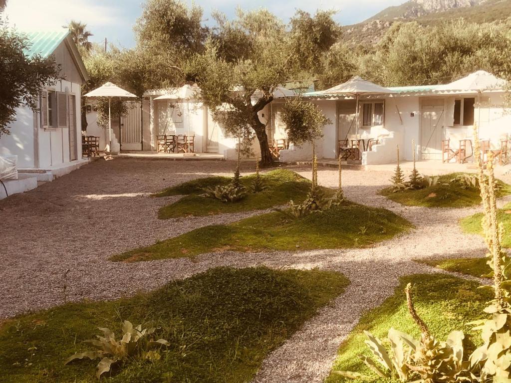 a house with a courtyard with a tree and chairs at Barreira Beachfront Rooms 6 in Kalamata