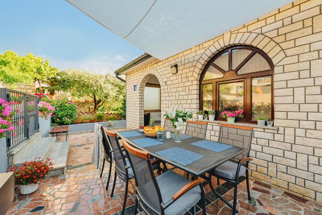 eine Terrasse mit einem Tisch und Stühlen an einer Ziegelwand in der Unterkunft Villa Luna in Poreč