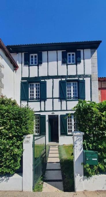une maison blanche et verte avec un portail devant elle dans l'établissement Charmant appartement avec jardin, à Larressore