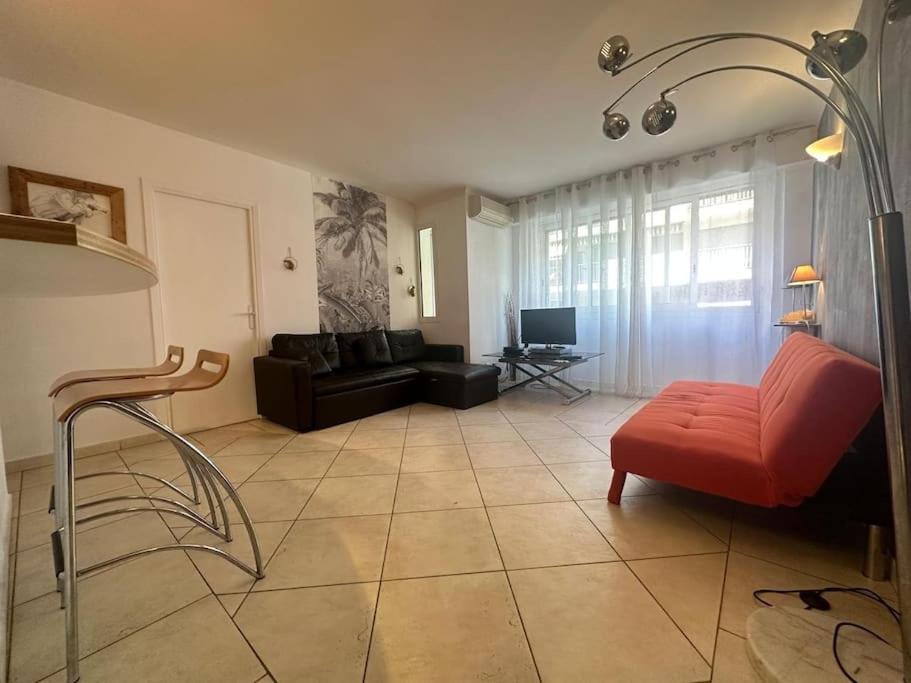un salon avec une chaise rouge et un canapé dans l'établissement Moderne 2pieces proche Martinez, à Cannes
