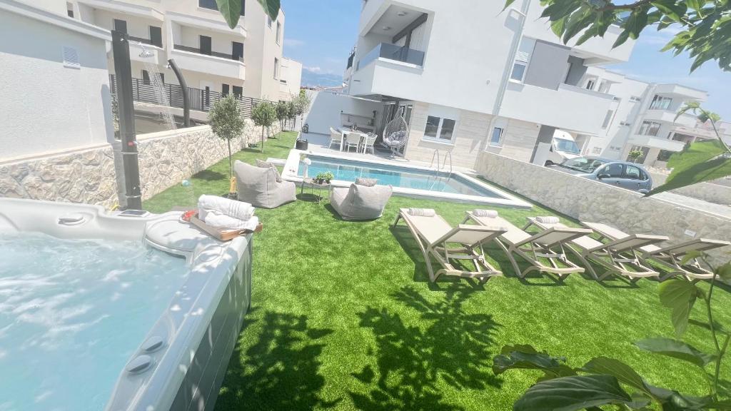 a yard with chairs and a swimming pool in a building at Luxury apartment Black Pearl Beluga with private Pool and Jacuzzi in Novalja