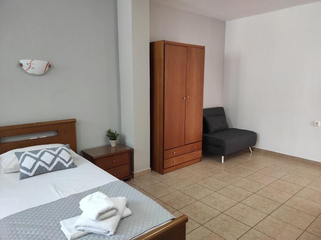 a bedroom with a bed and a chair and a cabinet at Vythos in Adamas