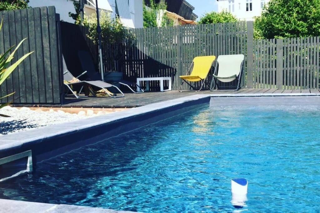une piscine avec des chaises et une clôture et une piscine dans l'établissement Appartement déco avec jardin et piscine, à Chambéry