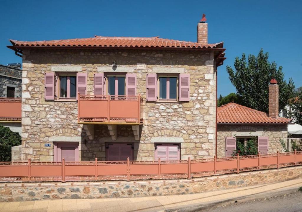 un vecchio edificio in pietra con finestre rosa e una recinzione di Villa Lakonia in Stoupa a Stoupa