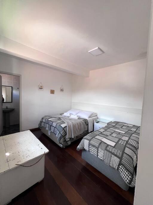 two beds in a room with a room with a table at Estadia das Gerais - Suíte Privativa 5 in Ouro Preto