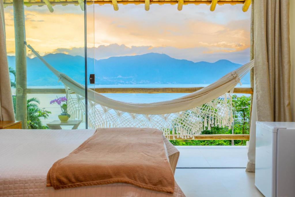 1 dormitorio con hamaca frente a una ventana en Suite Canto do Embauba, en Ilhabela