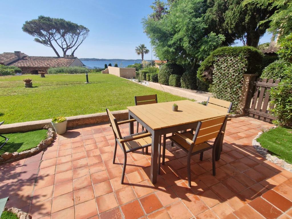 - une table et des chaises en bois sur une terrasse en briques dans l'établissement Studio climatisé avec piscine, parking, proche plage - Sainte-Maxime - FR-1-780-75, à Sainte-Maxime