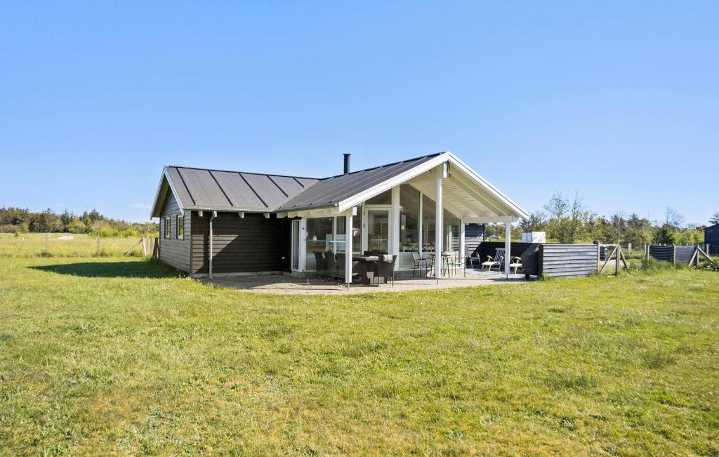 une petite maison avec un toit en gambrel sur un champ dans l'établissement 3 Bedroom Lovely Home In Ålbæk, à Ålbæk